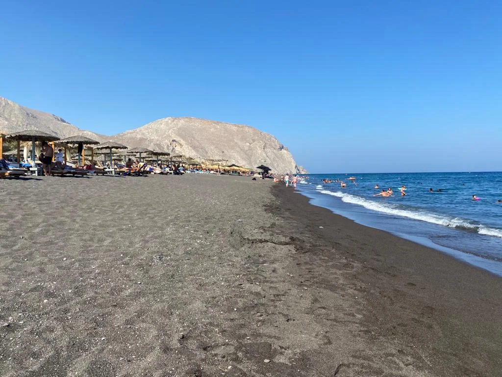 The black-sand Perivolos beach lined with straw umbrellas below Mesa Vouno, Santorini