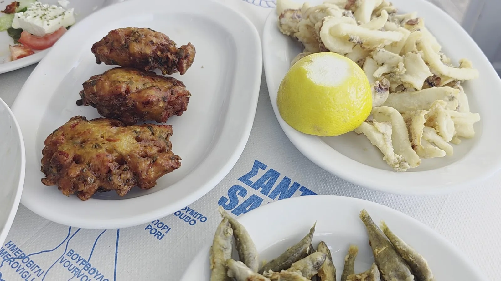 A spread of Greek seafood meze — tomato fritters, fried calamari and small fish — at Fratzeskos Fish Tavern in Perissa