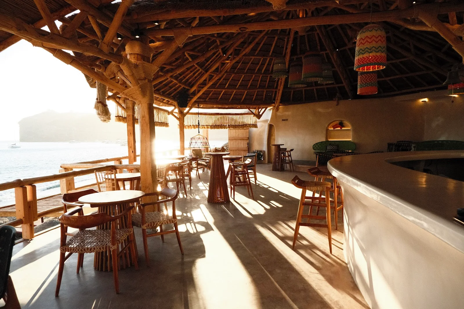 The bamboo-and-thatch interior and curved bar of Theros Wave Bar at sunset, Vlychada