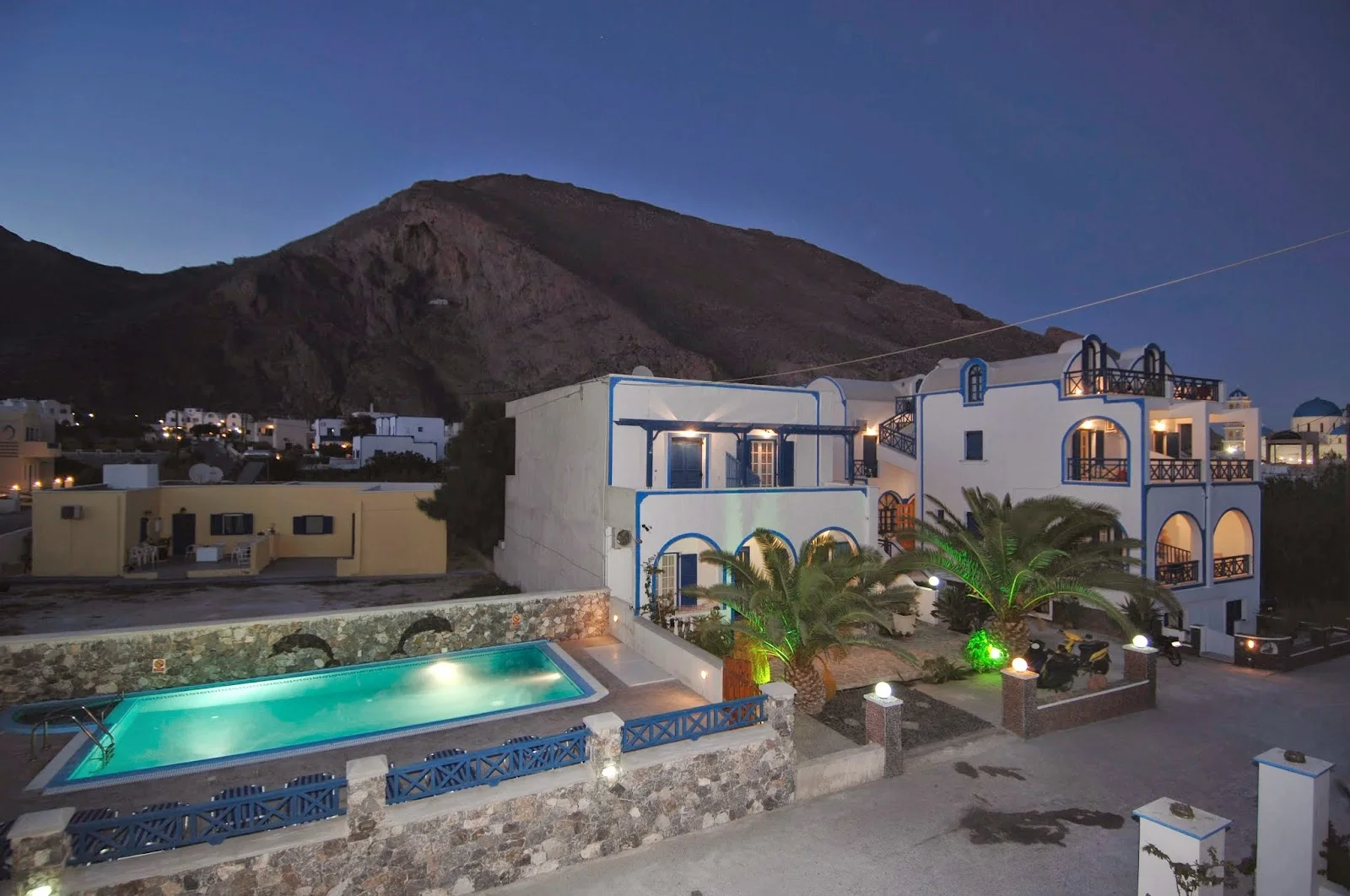The white-and-blue Villa Aretousa with its pool below Mesa Vouno in Perissa, Santorini