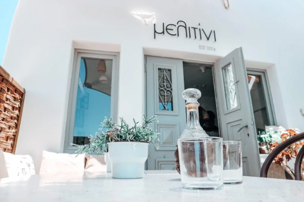 The whitewashed facade and sign of Melitini meze restaurant in Oia, Santorini