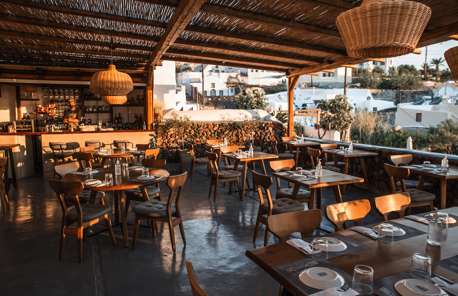 The warmly lit, wicker-lamp-hung covered terrace of Meze Meze restaurant near Oia, Santorini
