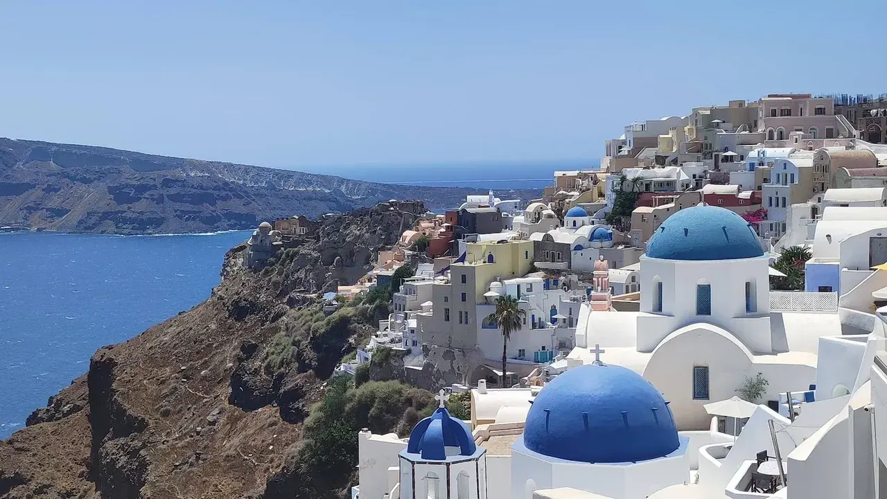The blue-domed churches and whitewashed cave houses of Oia above the Santorini caldera