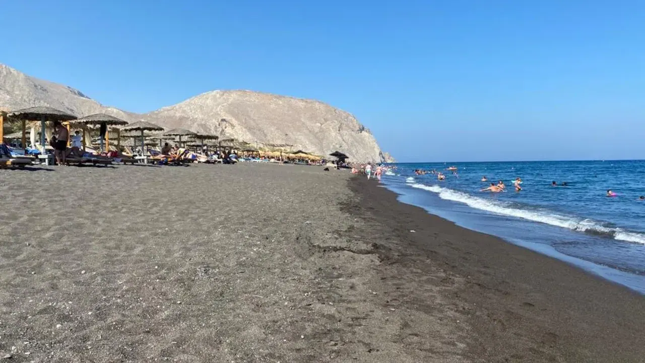 Perivolos beach on Santorini's southeast coast, a long stretch of black volcanic sand by the sea