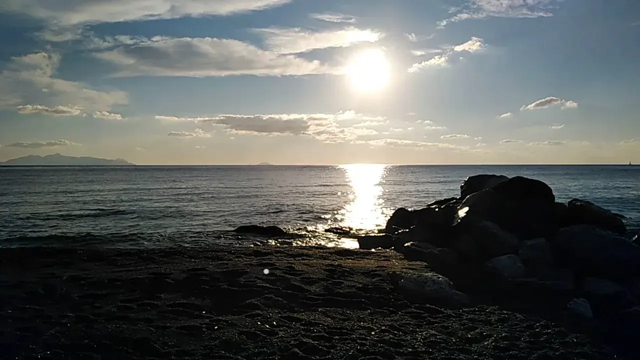 The long black-sand beach at Perissa on Santorini's southeast coast, with sunbeds and calm sea
