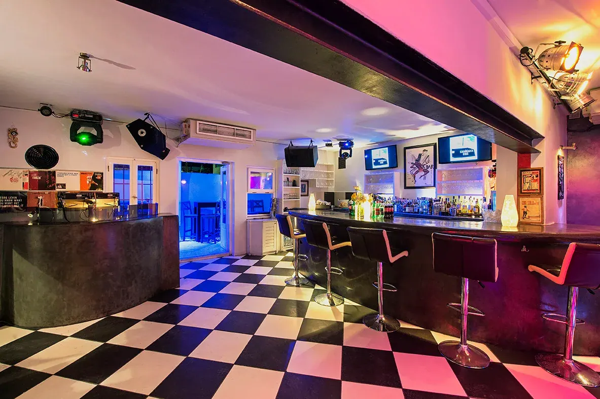 The checkerboard floor and long curved bar under stage lights at Casablanca Soul, Fira