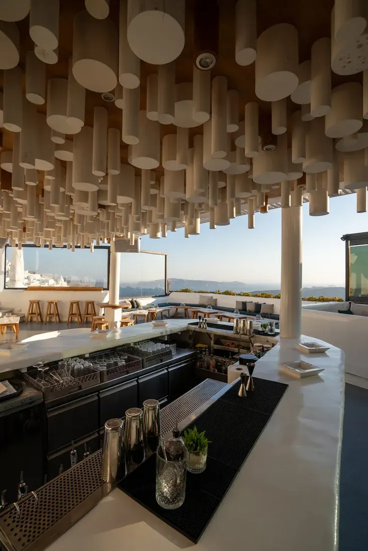 The hanging pale-wood cylinder ceiling and caldera-view terrace at Tango cocktail bar, Fira