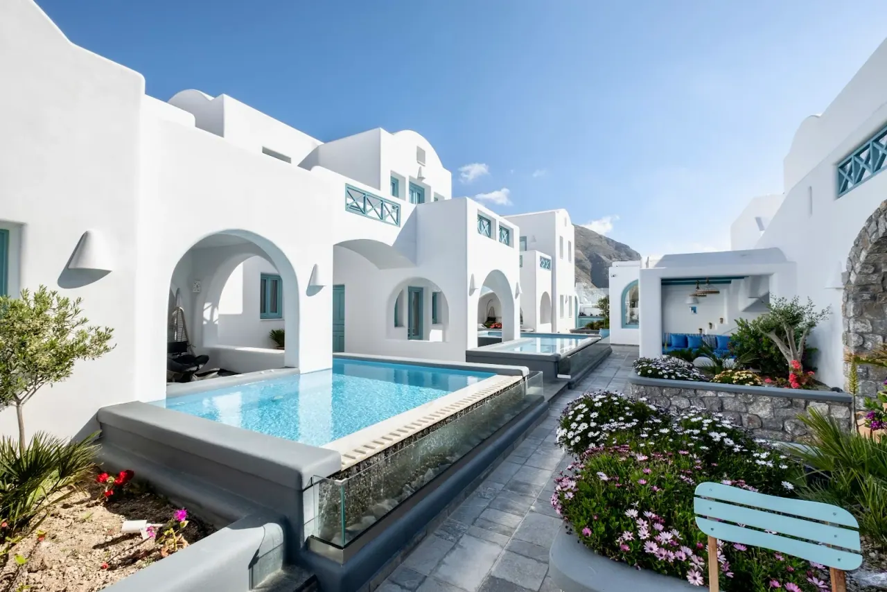 White Cycladic suites with private plunge pools along a flower-lined lane at Anastasia Princess in Perissa, Santorini