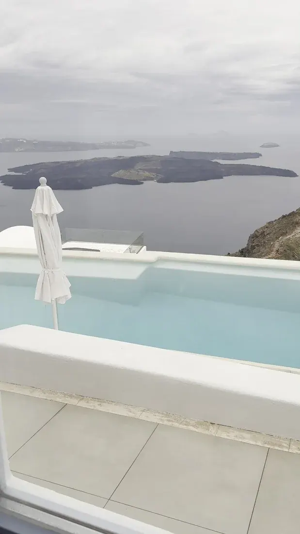 A plunge pool and umbrella on a white terrace at Astra Suites looking over the caldera in Imerovigli, Santorini