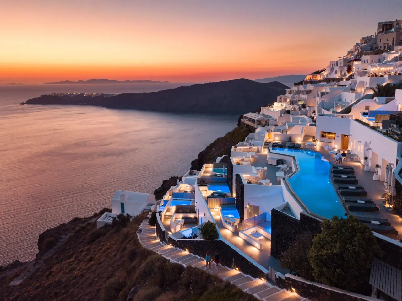 The white cliffside terraces and infinity pool of Grace Hotel Santorini over the caldera at sunset in Imerovigli