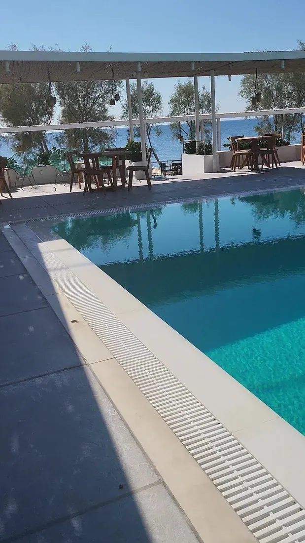 The pool and sea-view terrace of Kamari Beach Hotel behind the black-sand beach in Kamari, Santorini