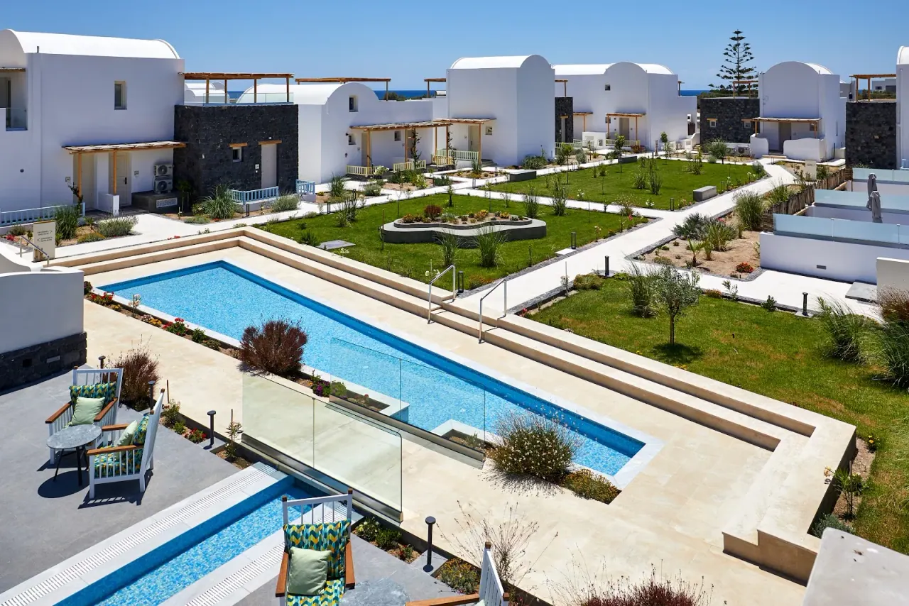 The white barrel-vaulted villas, gardens and pools of Sea Breeze Santorini Beach Resort near the beach in Perivolos