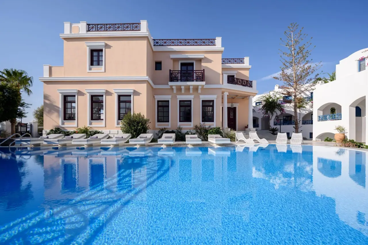 The neoclassical peach-and-white Veggera Hotel and its large pool on the Perissa–Perivolos beachfront, Santorini