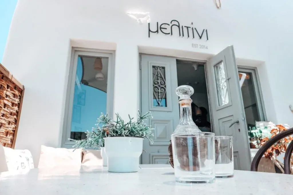 The whitewashed facade and sign of Melitini meze restaurant in Oia, Santorini