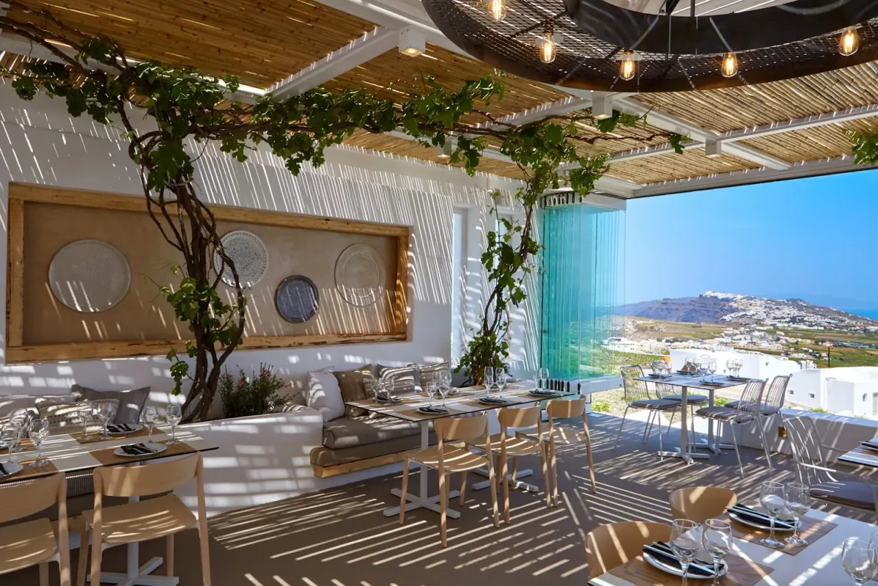 The vine-shaded pergola terrace of Pyrgos Restaurant with a panoramic view over the village to the sea, Santorini