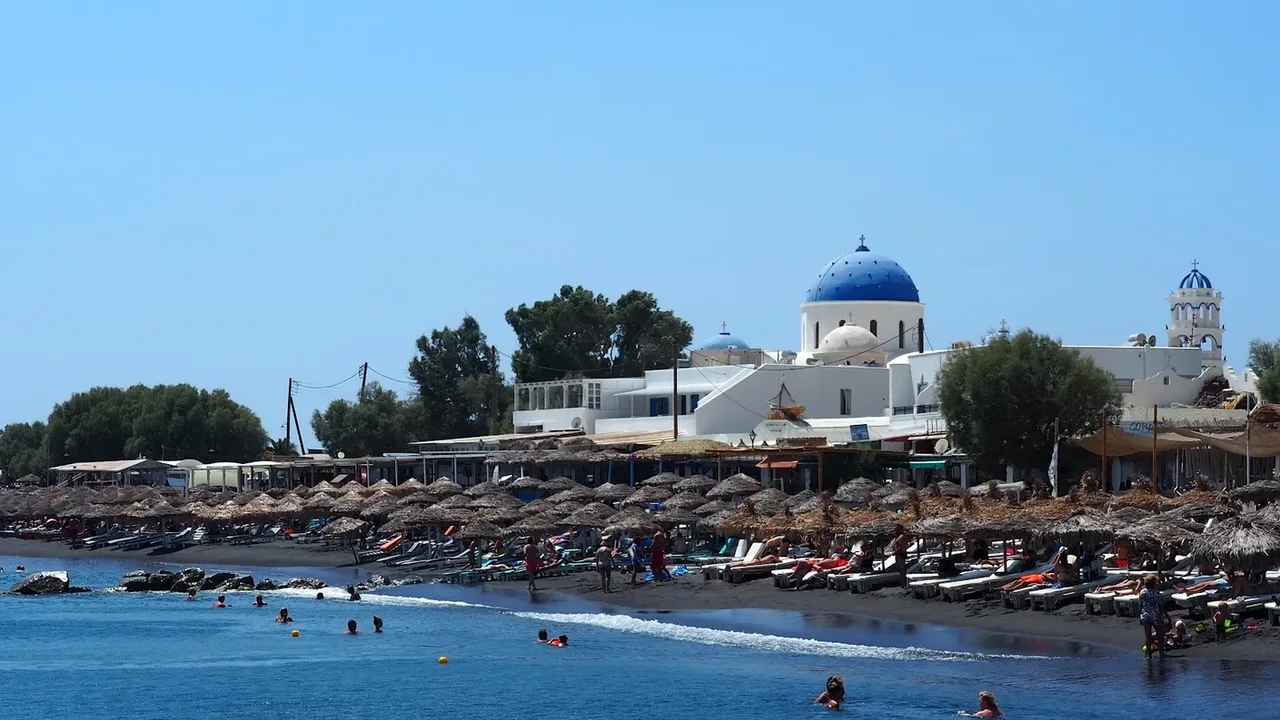 The long black-sand beach of Perissa below the rock of Mesa Vouno, Santorini