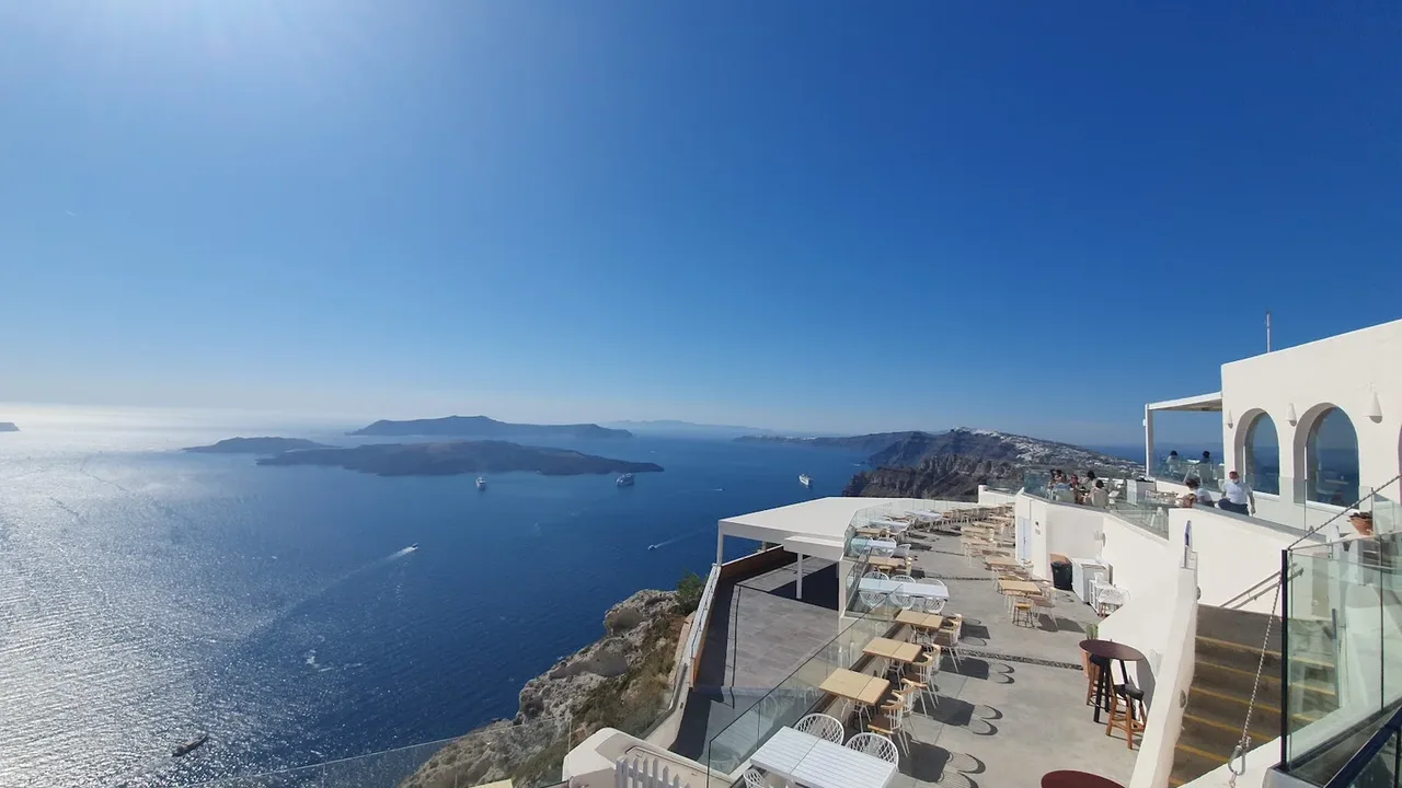 A caldera-view wine-tasting terrace above the Santorini caldera at golden hour