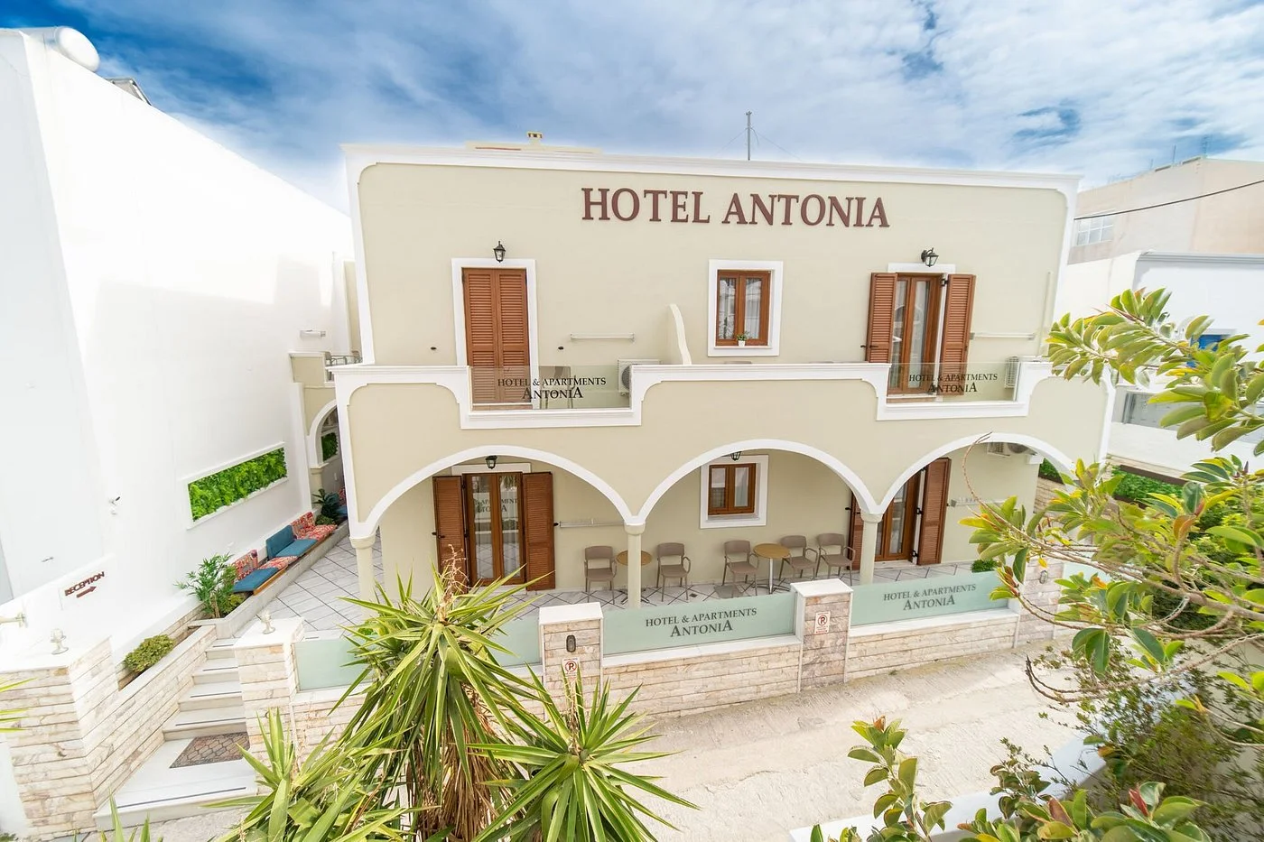 The cream arched façade of Hotel Antonia with its brown shutters on a lane in Fira, Santorini