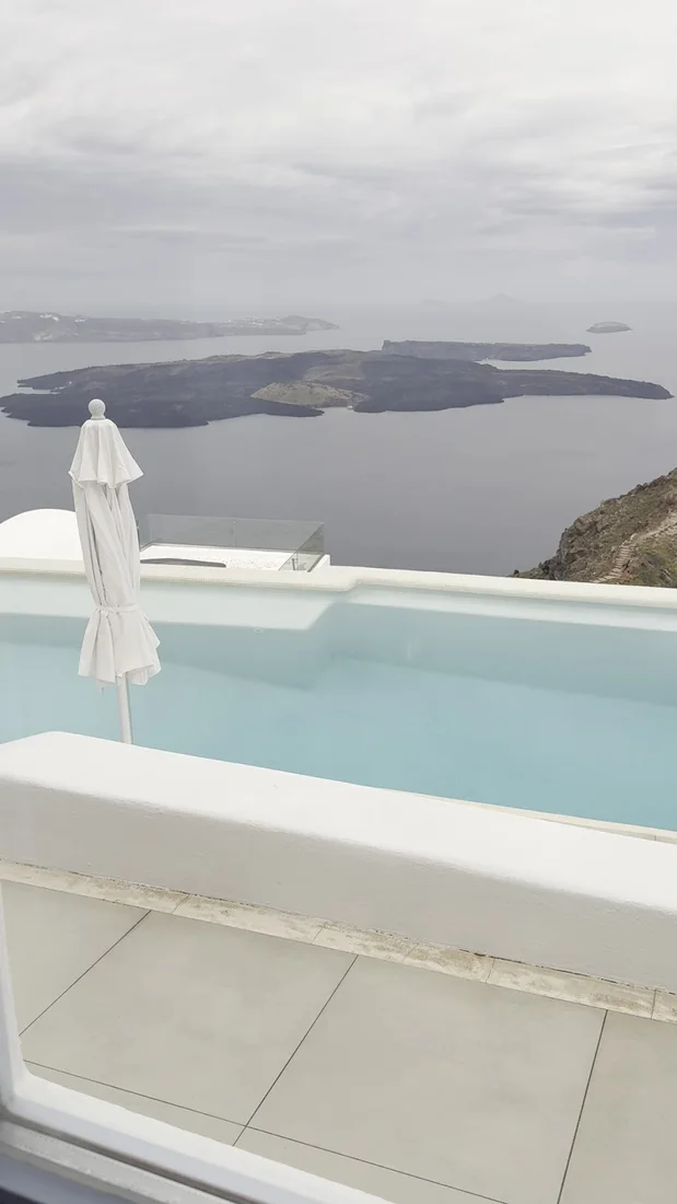 A plunge pool and umbrella on a white terrace at Astra Suites looking over the caldera in Imerovigli, Santorini