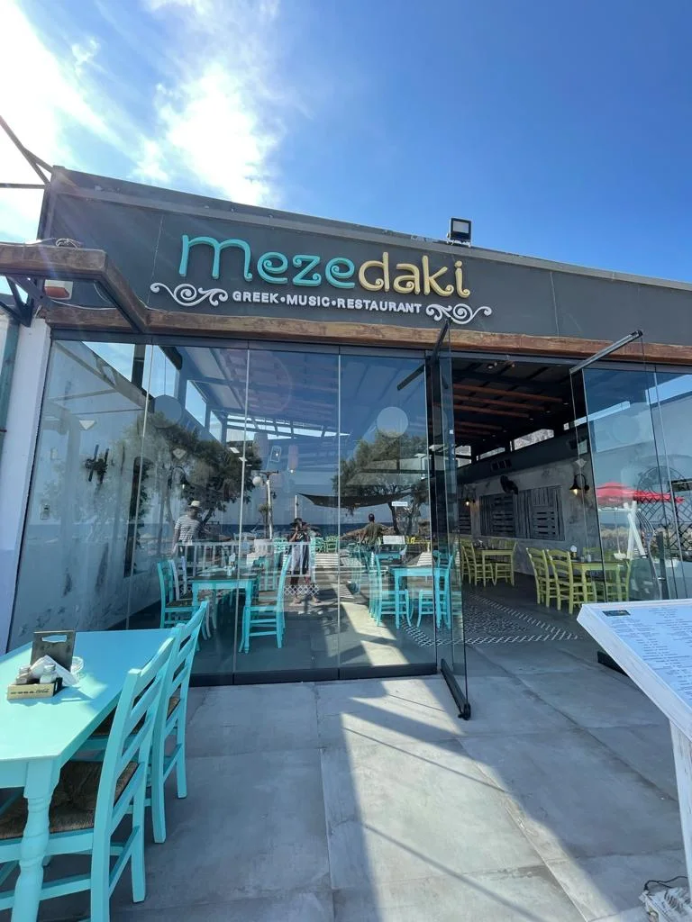 The turquoise-chaired terrace and sign of Mezedaki Greek music restaurant on the Perissa beach road, Santorini