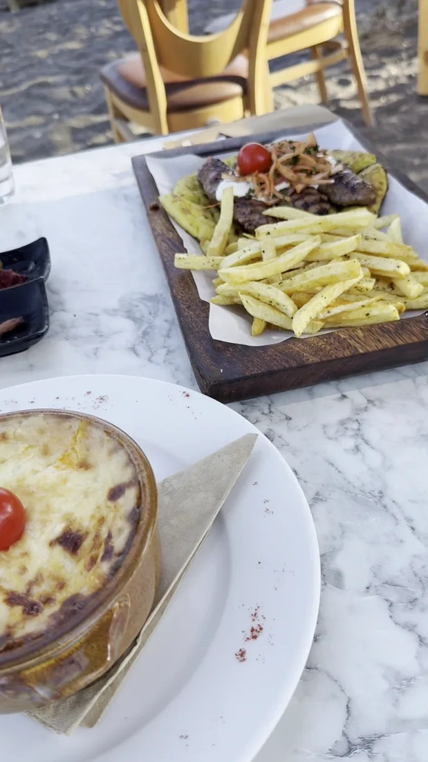 A plate of grilled souvlaki with chips and a baked dish at Ntomatini restaurant in Perissa, Santorini