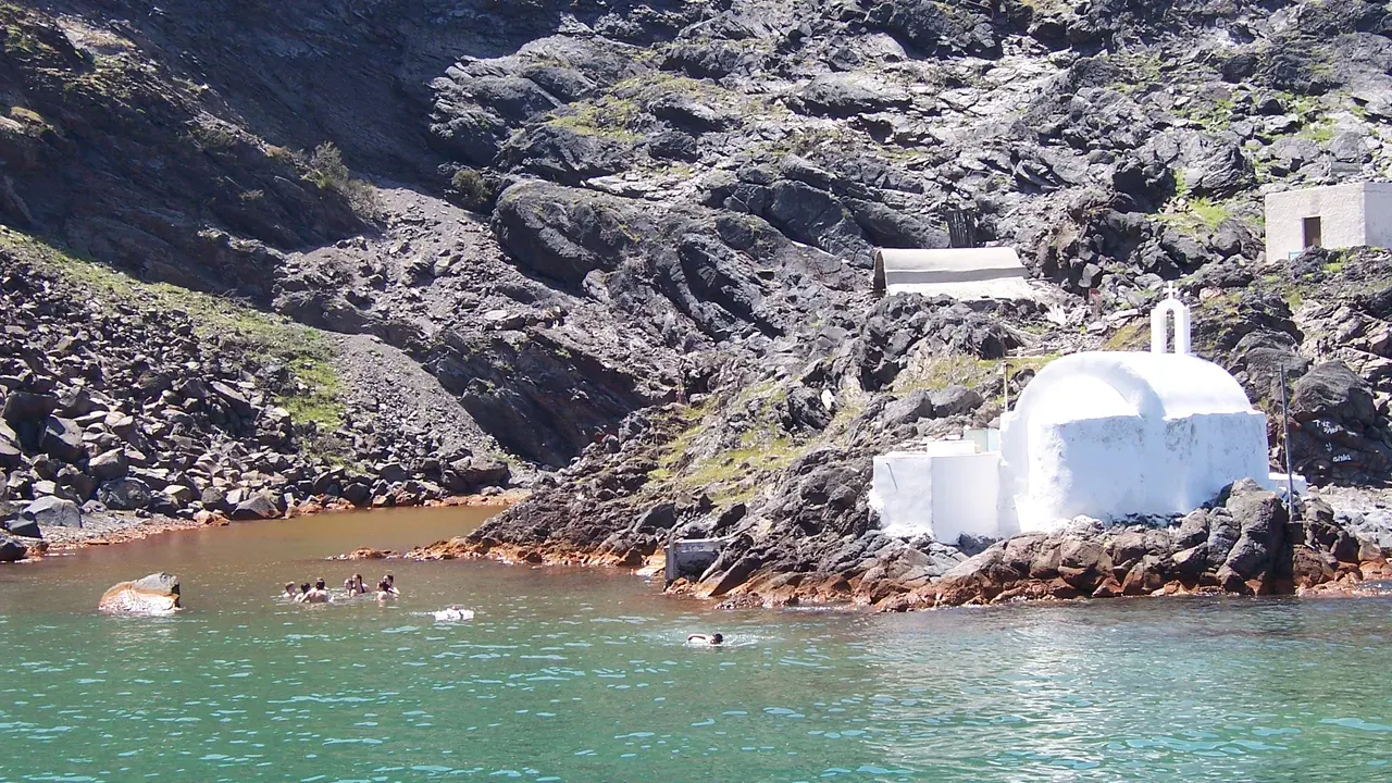 The warm ochre-tinted hot-spring cove off the volcanic islet of Palea Kameni in the Santorini caldera