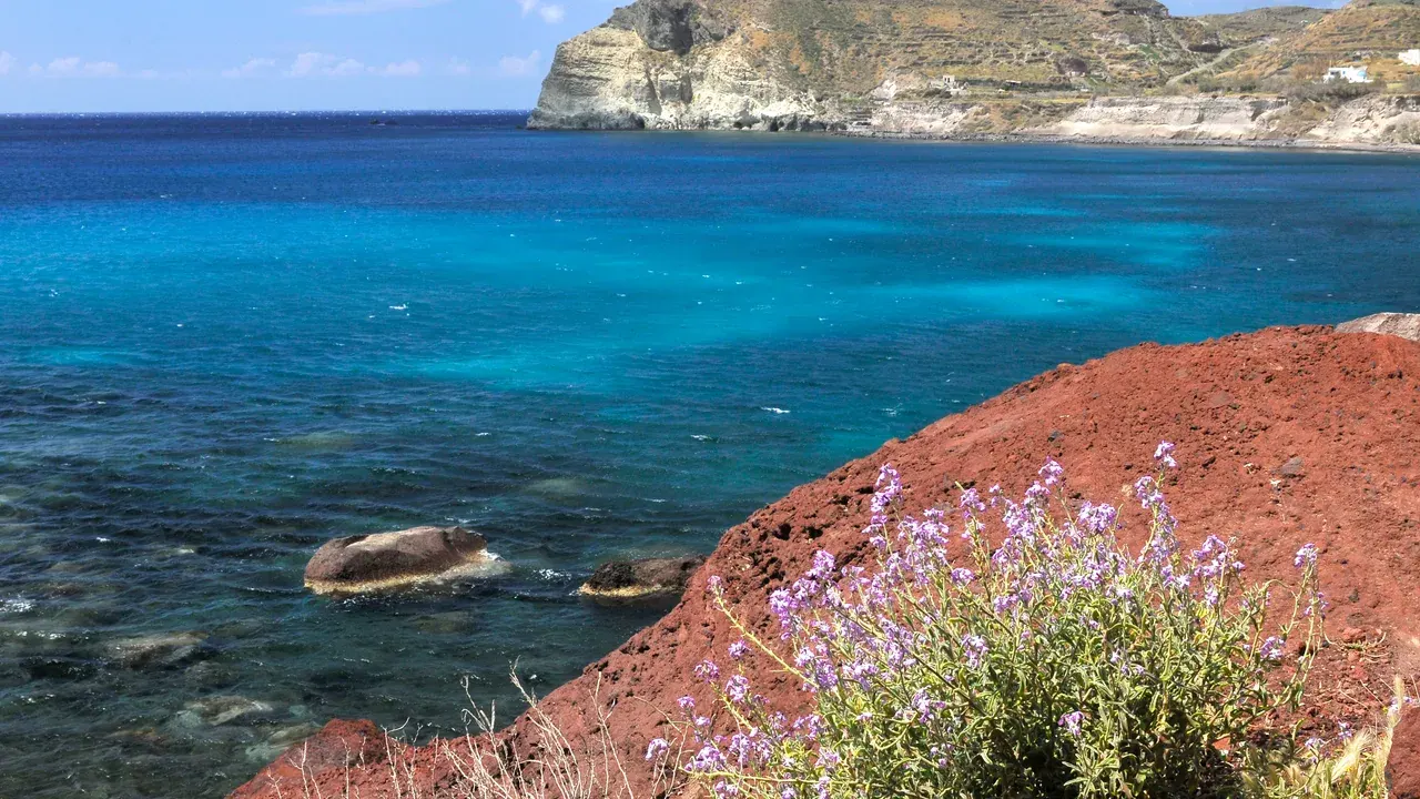 The red volcanic cliffs and swimming cove of Santorini's Red Beach near Akrotiri